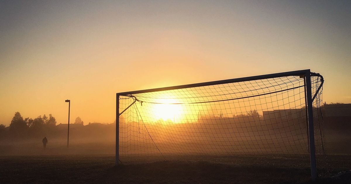 Portería a contraluz con el sol del atardecer y niebla