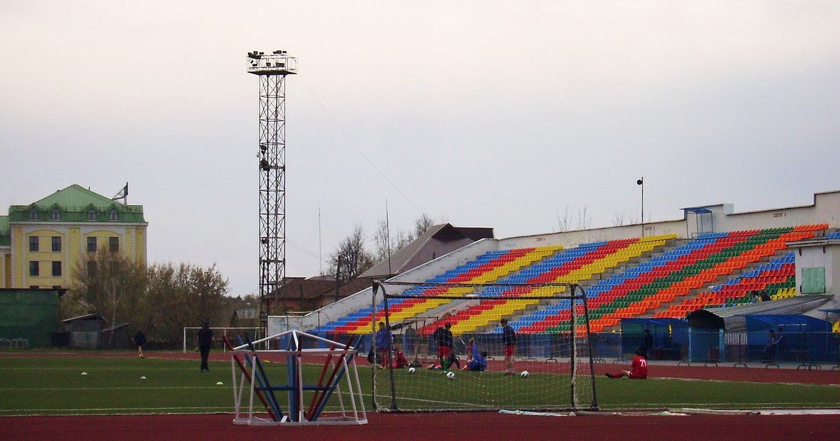 Estadio modesto con una tribuna de asientos de colores y una torre de focos