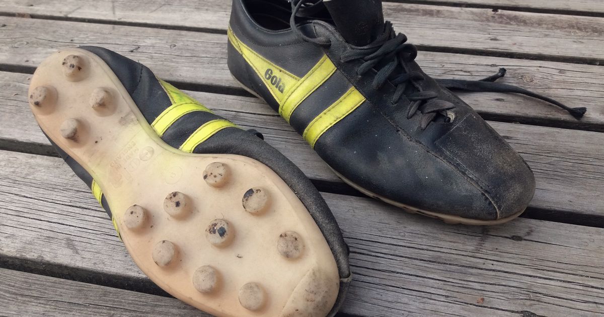 Botines de fútbol viejos sobre un banco de madera