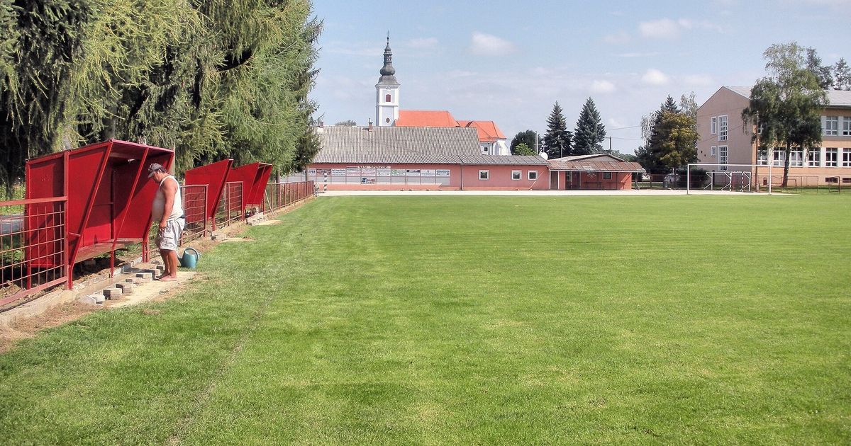 Banquillos rojos al borde de una cancha de pueblo