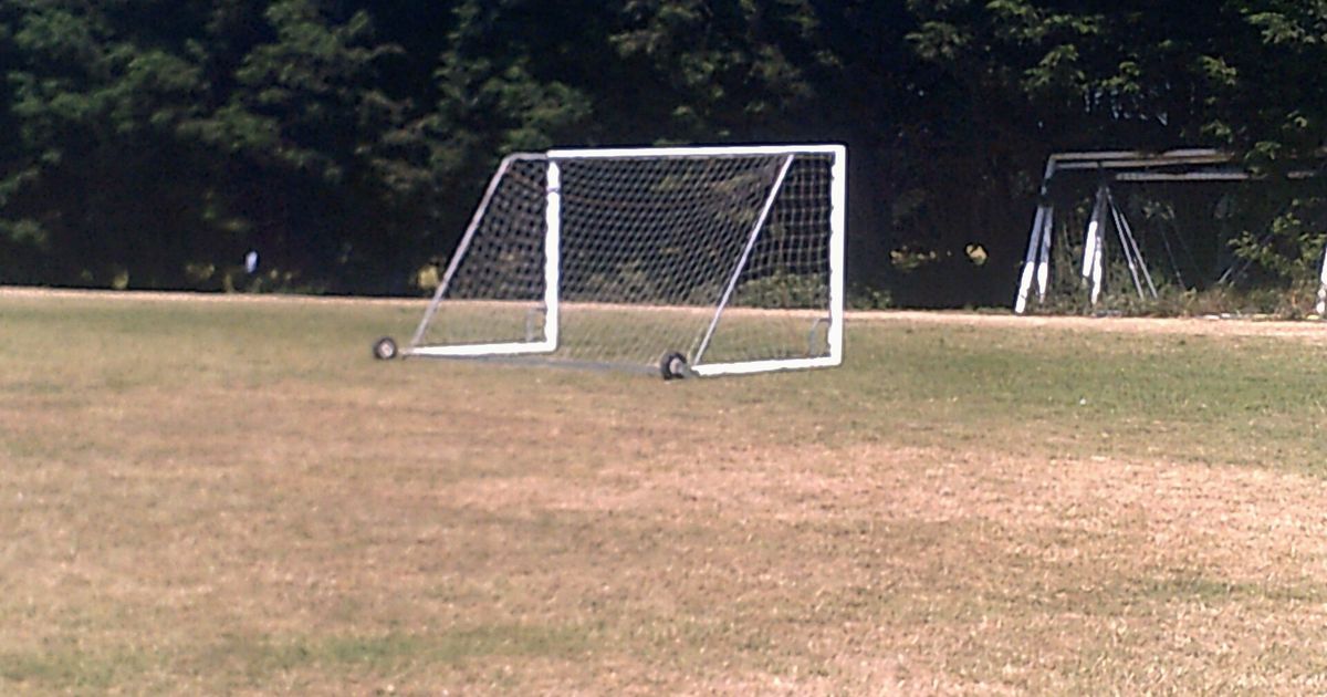 Cancha de césped seco con una portería al fondo