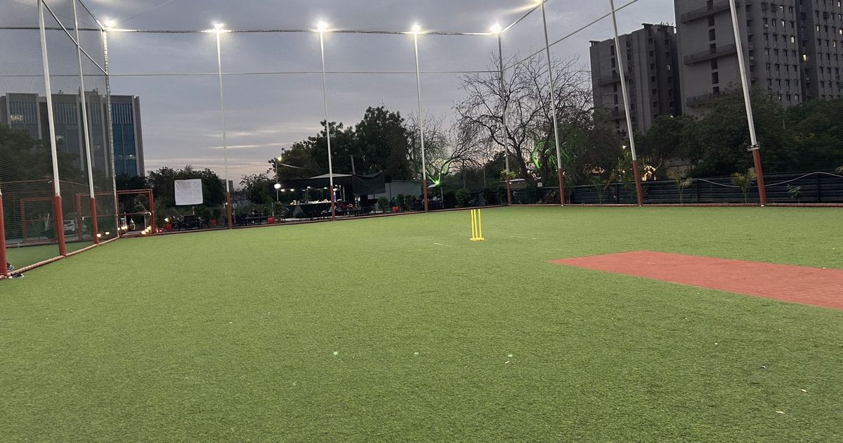 Cancha de césped con los focos encendidos al anochecer
